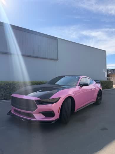 Ford Mustang wrapped in pink with a black hood stripe, front three-quarter view